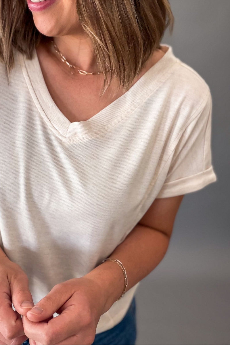 Person wearing a oatmeal with subtle stripe t-shirt with a blurred background