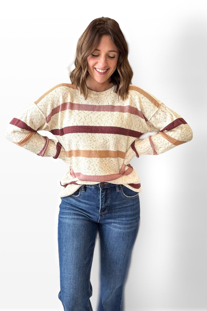 Woman wearing a striped sweater and blue jeans on a white background