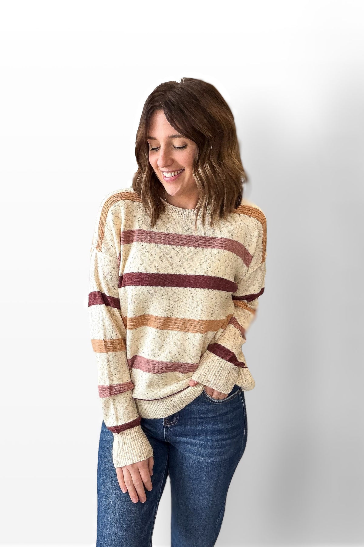 Woman wearing a striped sweater and jeans on a white background