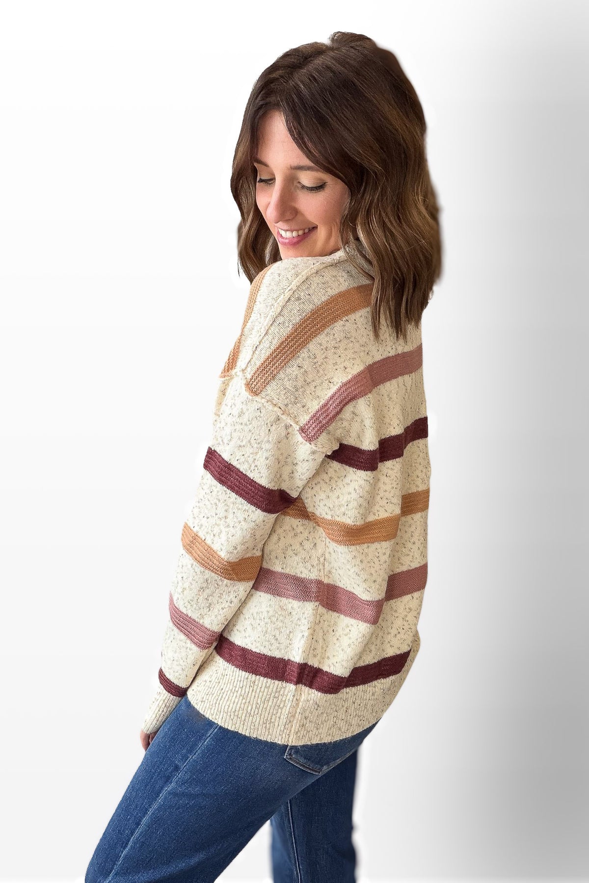 Woman wearing a striped sweater and blue jeans on a white background
