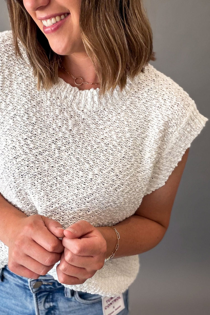 Off white textured short sleeve knit sweater with a breathable open-knit design, ribbed trim, and relaxed fit styled with light wash denim showing texture upclose