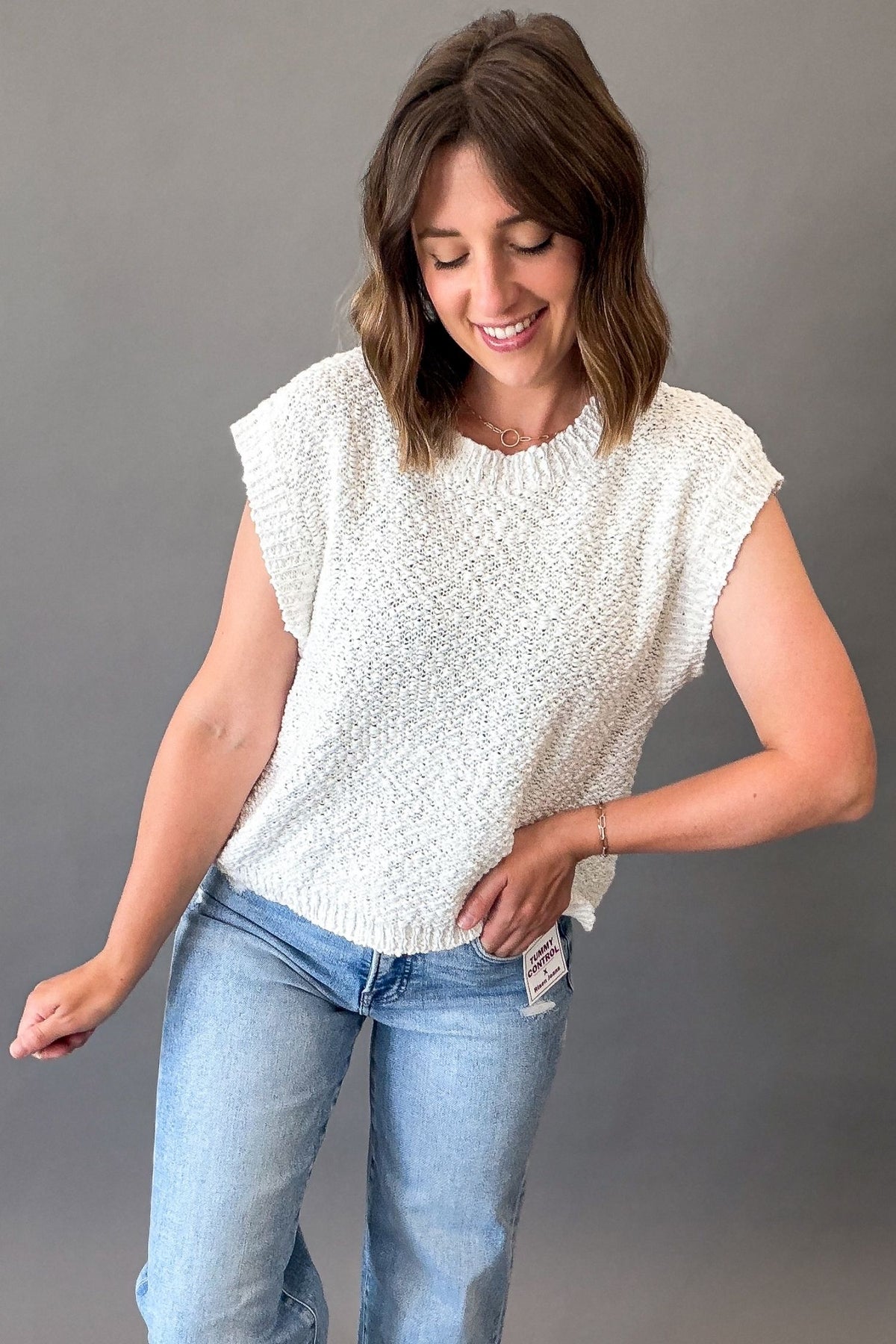 Off white textured short sleeve knit sweater with a breathable open-knit design, ribbed trim, and relaxed fit styled with light wash denim.