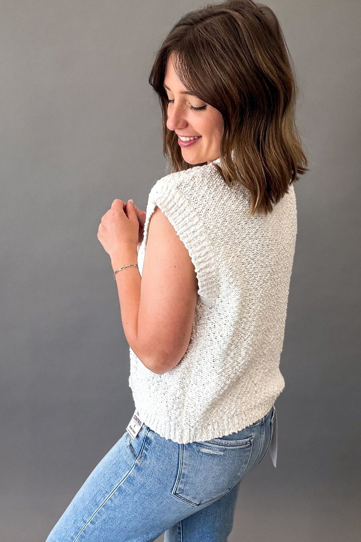 Off white textured short sleeve knit sweater with a breathable open-knit design, ribbed trim, and relaxed fit styled with light wash denim.