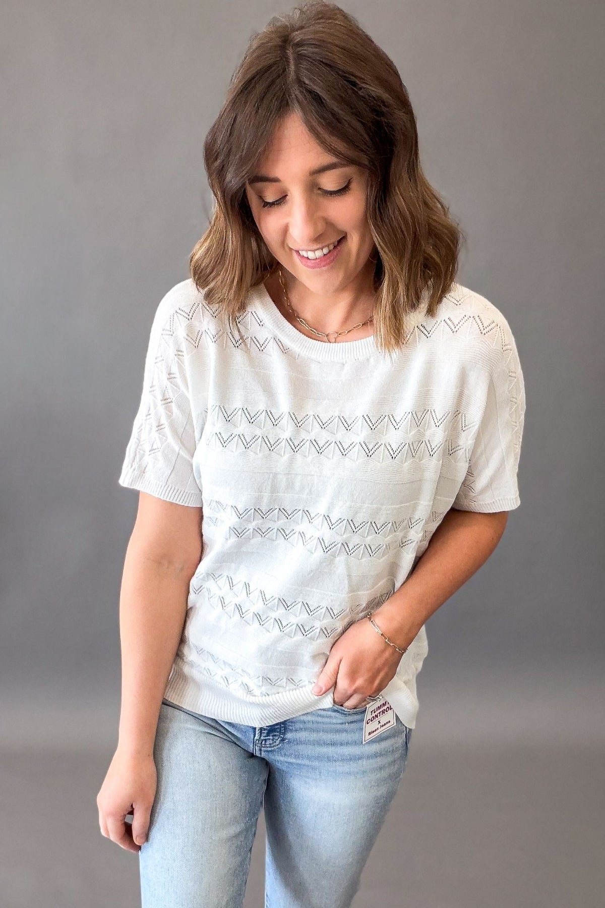 Woman wearing an off white pointelle knit short sleeve top with lightweight soft fabric and stretch, casual versatile women’s top