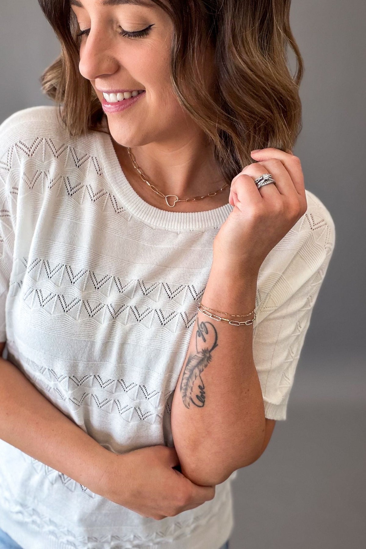 Woman wearing an off white pointelle knit short sleeve top with lightweight soft fabric and stretch, casual versatile women’s top