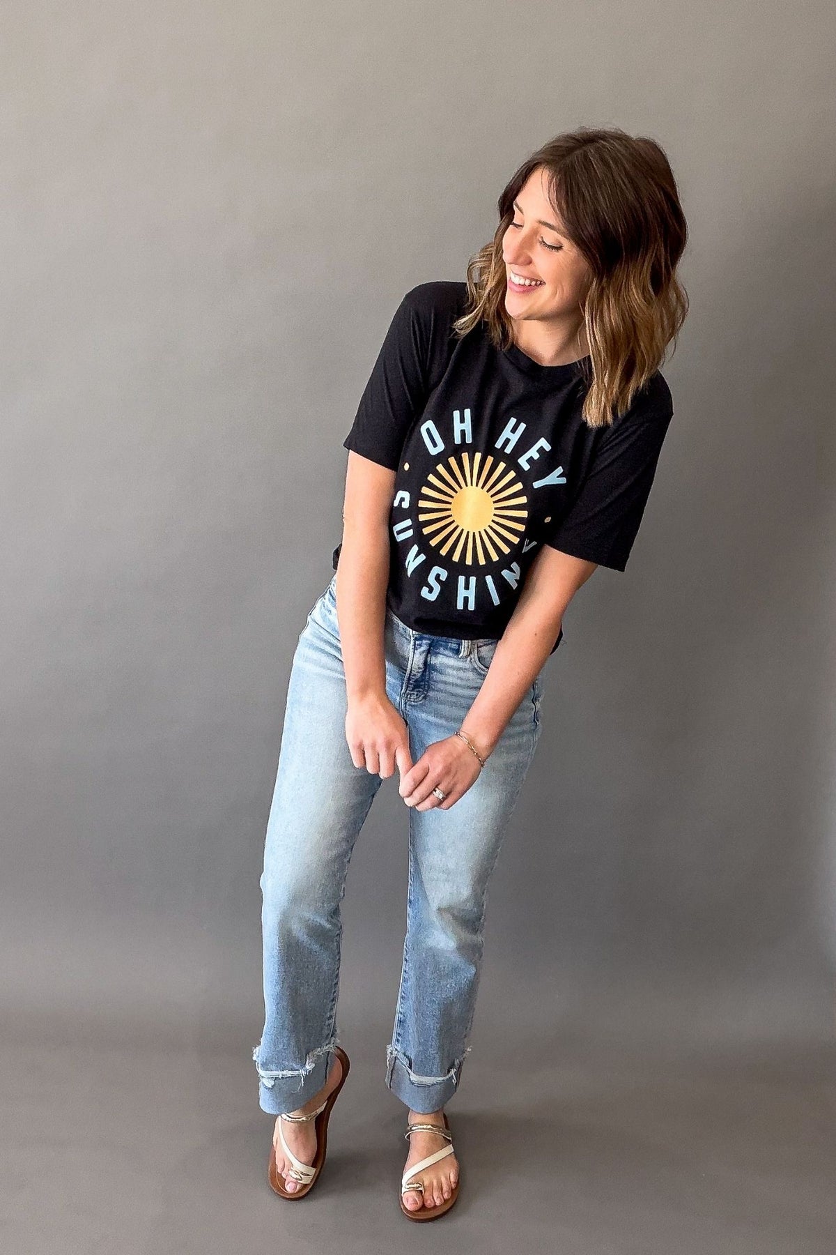 Woman wearing a black Oh Hey Sunshine graphic tee with yellow sun graphic and relaxed casual summer outfit