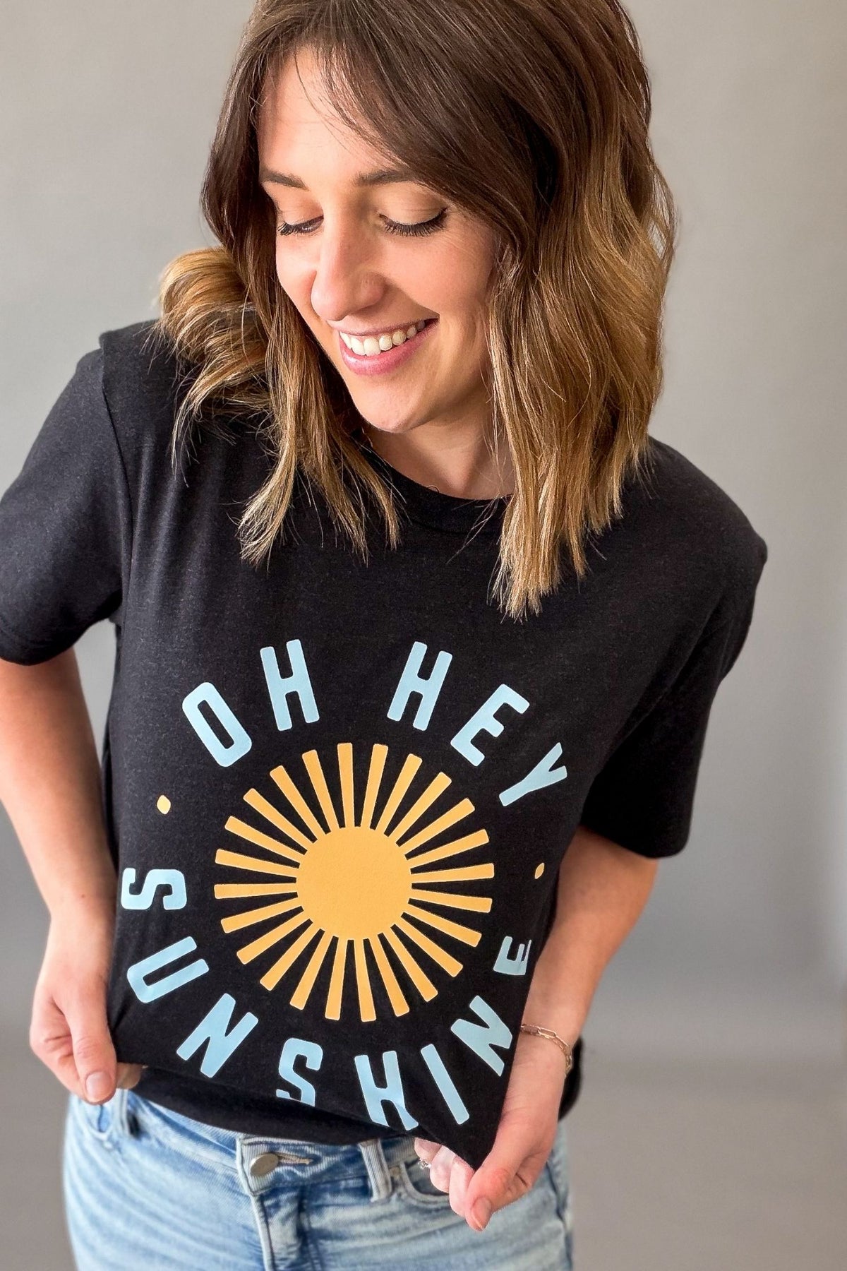 Woman wearing a black Oh Hey Sunshine graphic tee with yellow sun graphic and relaxed casual summer outfit