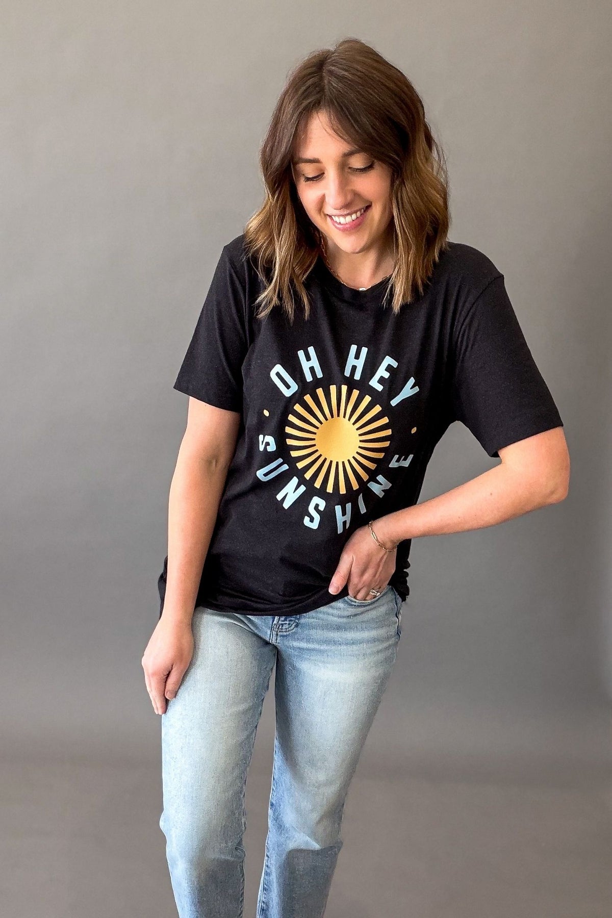 Woman wearing a black Oh Hey Sunshine graphic tee with yellow sun graphic and relaxed casual summer outfit