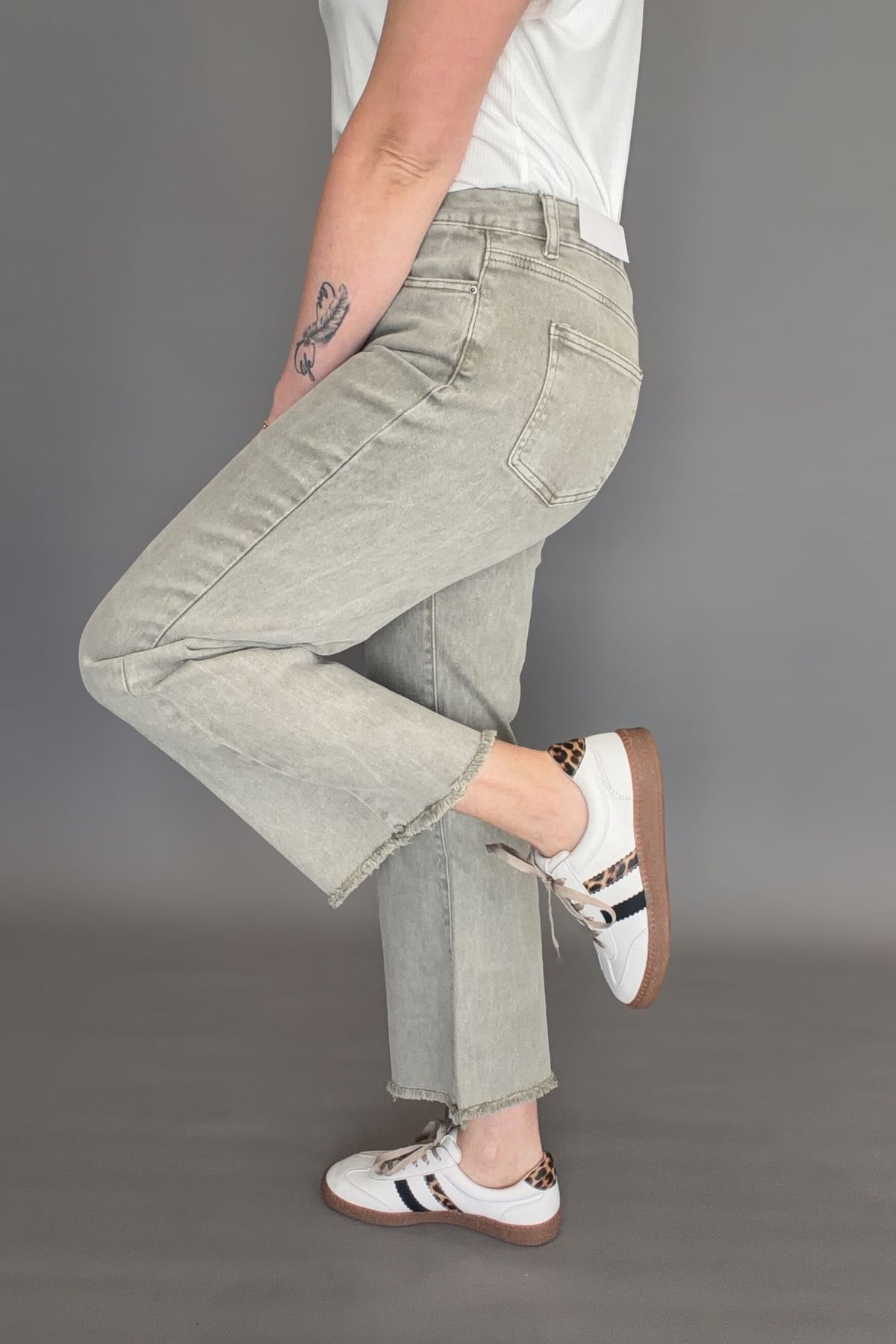 Side view of olive high rise cropped bootcut jeans showing slight flare and raw hem detail.