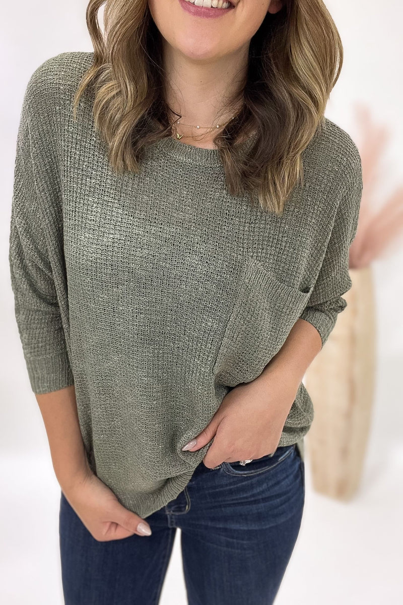 Woman wearing a green sweater and blue jeans against a white background