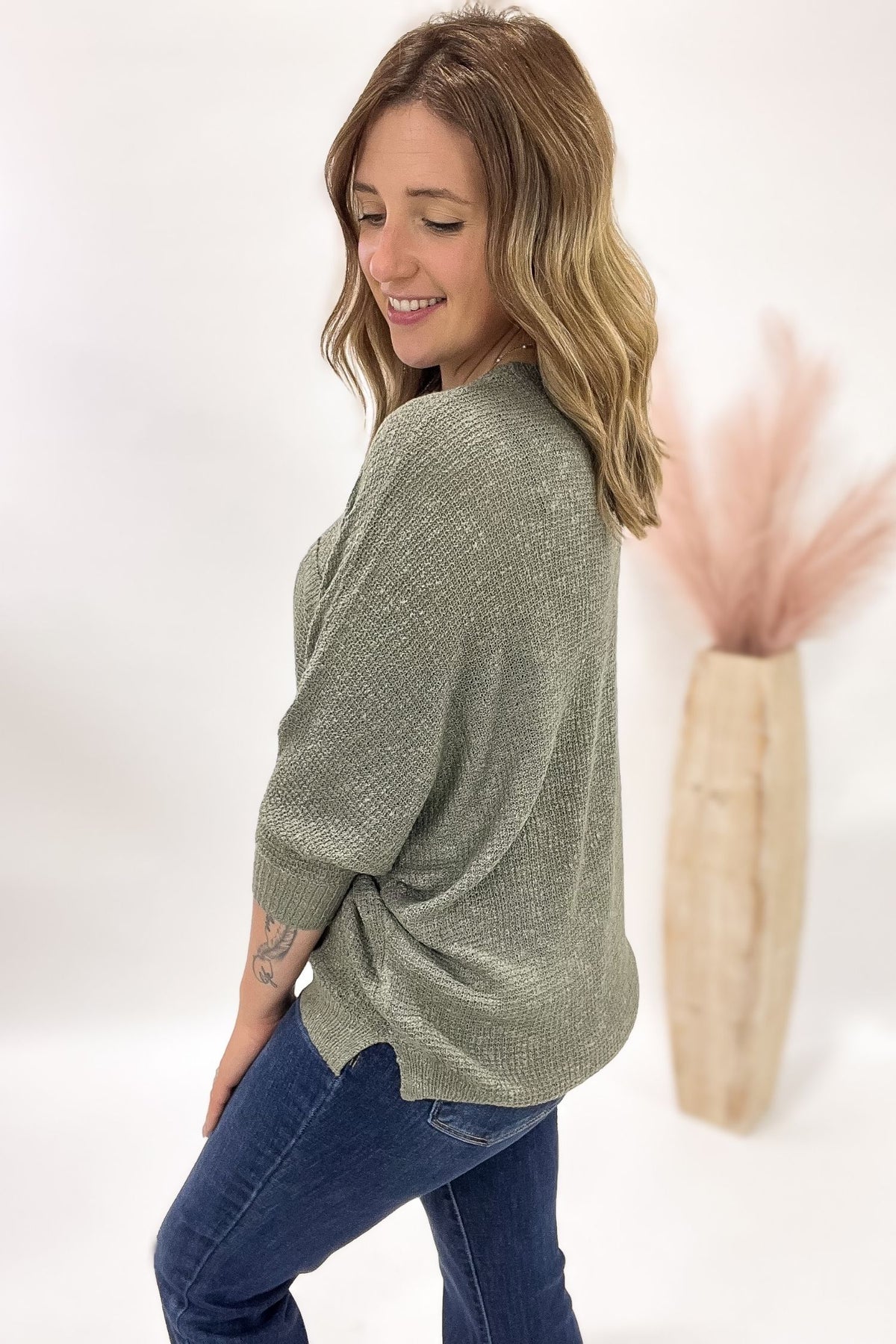 Woman wearing a green sweater and blue jeans against a white background
