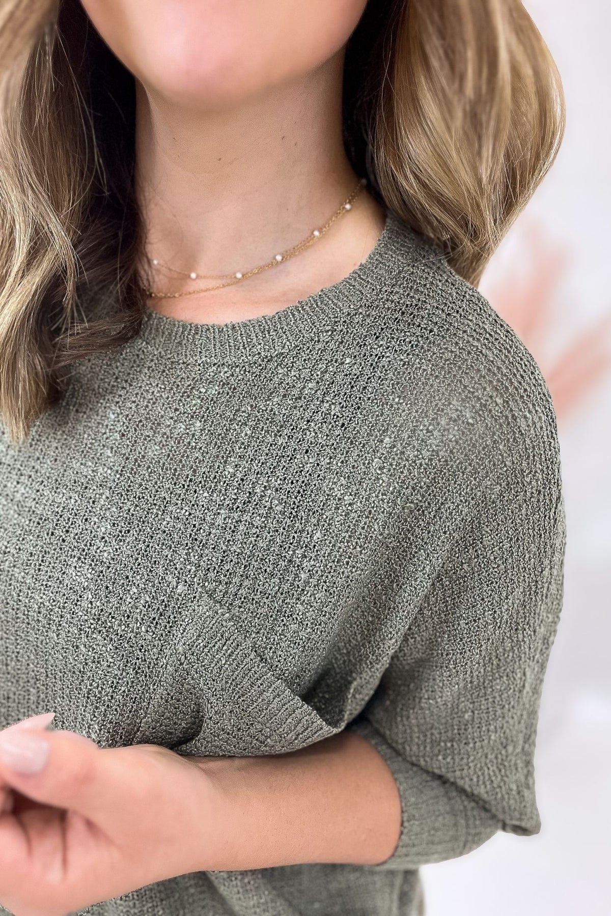 Person wearing a green knit sweater with a blurred background