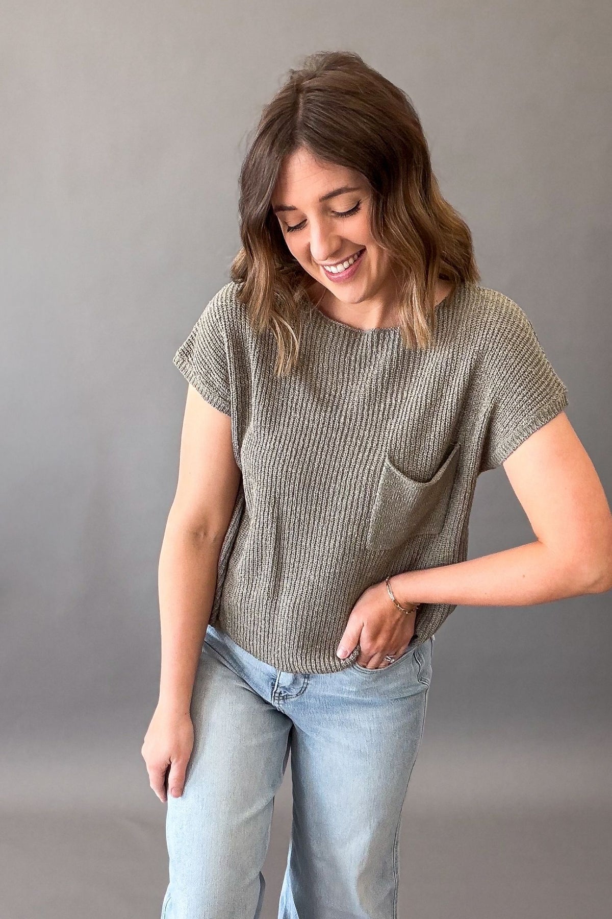 woman wearing a textured olive tee with a chest pocket and light wash jeans