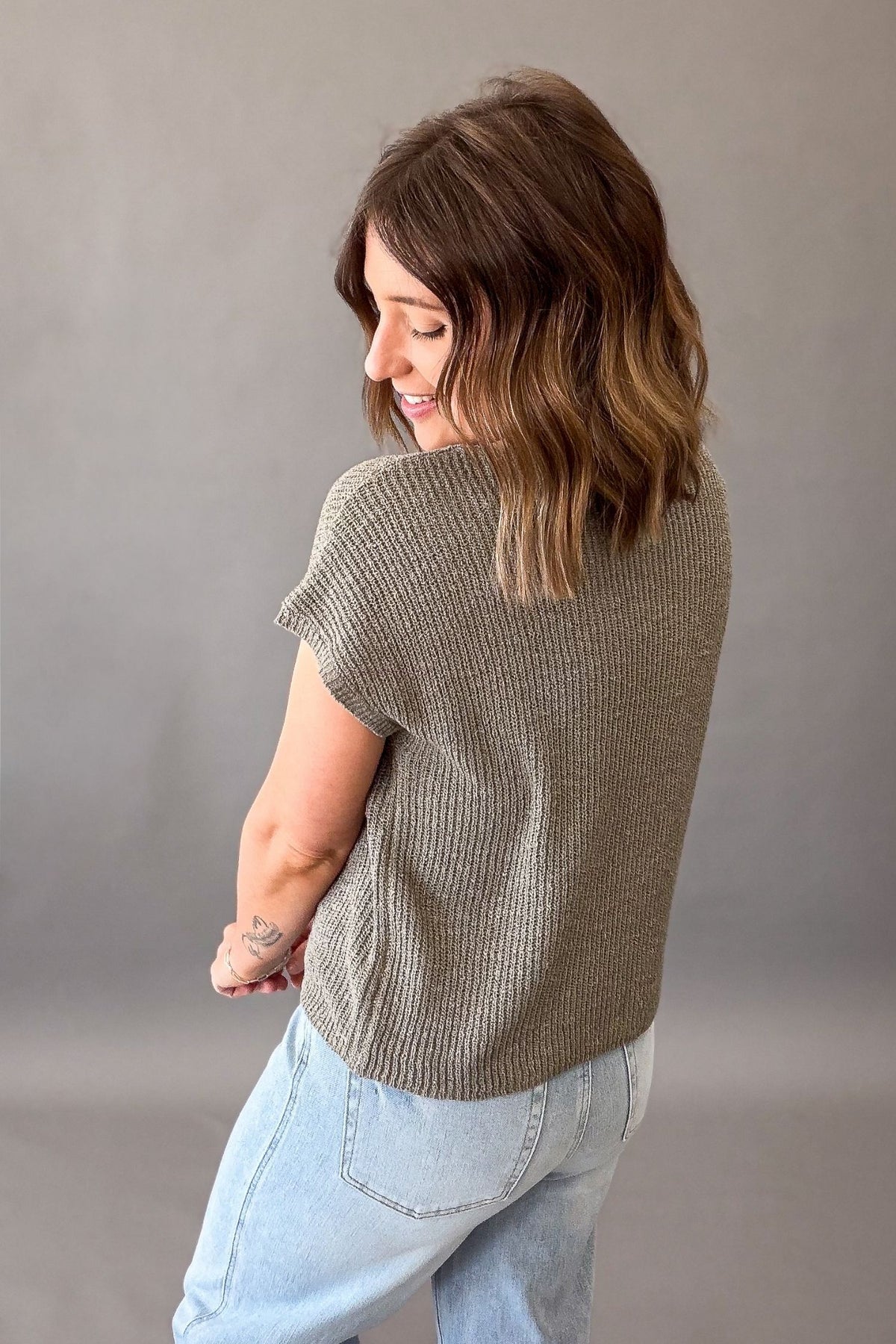 woman wearing an olive textured short sleeve showing back details