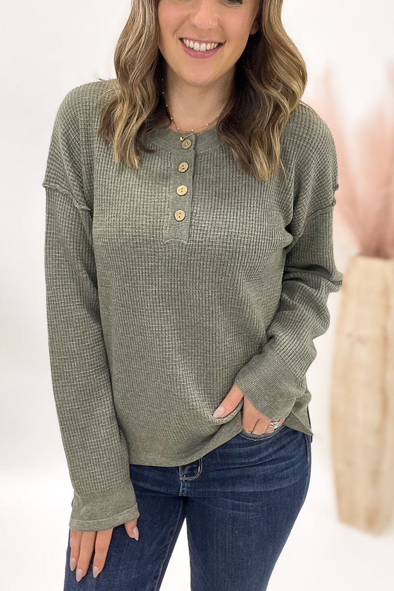 Woman wearing a green waffle long-sleeve shirt with buttons on a white background