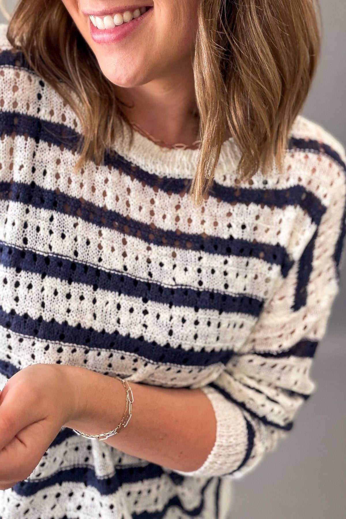 Person wearing a white and navy striped sweater with a blurred background