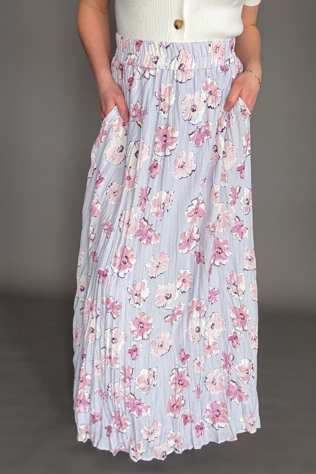 Orchid floral maxi skirt with elastic waistband and soft floral print styled with ivory cardigan showing it has pockets.