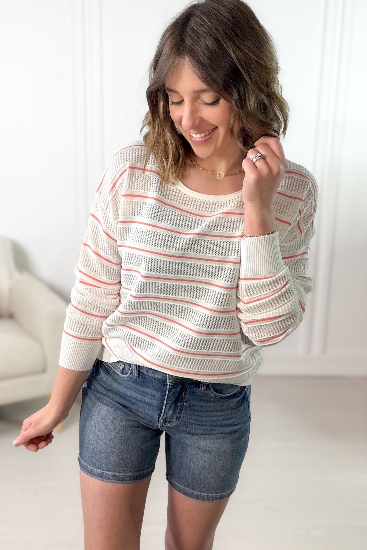 White and papaya striped pointelle knit pullover styled with denim shorts.