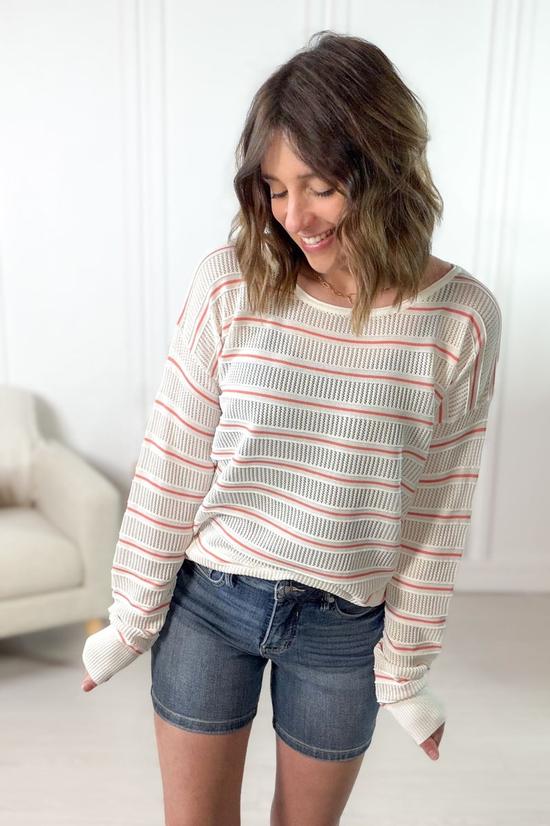 White and papaya striped pointelle knit pullover styled with denim shorts.