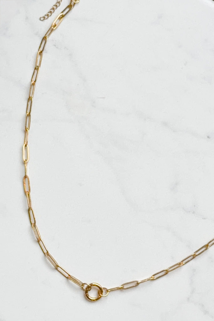 Gold chain necklace on a white marble surface