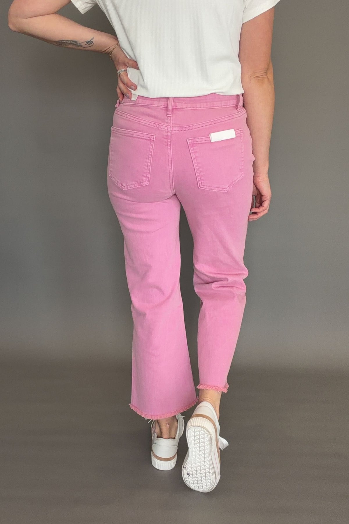 Back view of pink acid wash high rise bootcut jeans showing cropped length and fitted waist.