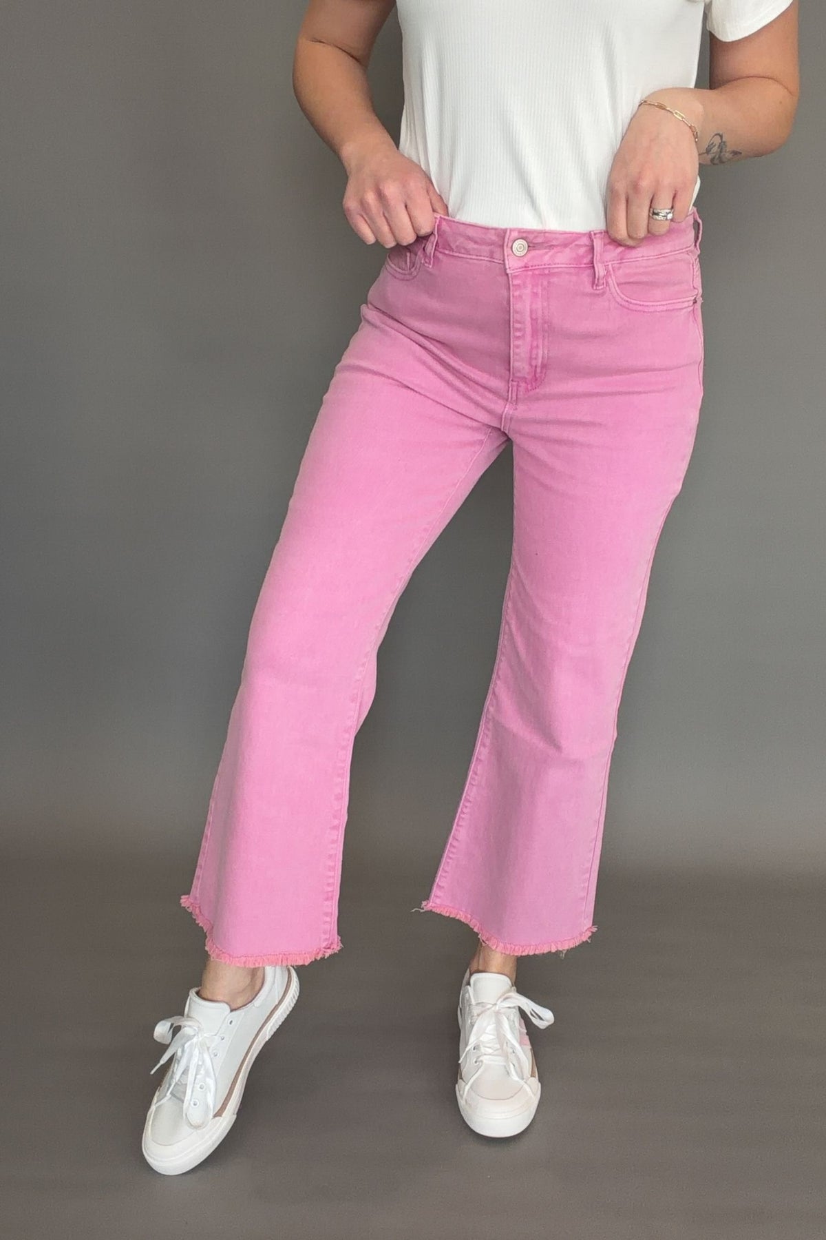 Pink acid wash crop bootcut jeans styled with white tee and sneakers for spring boutique outfit.