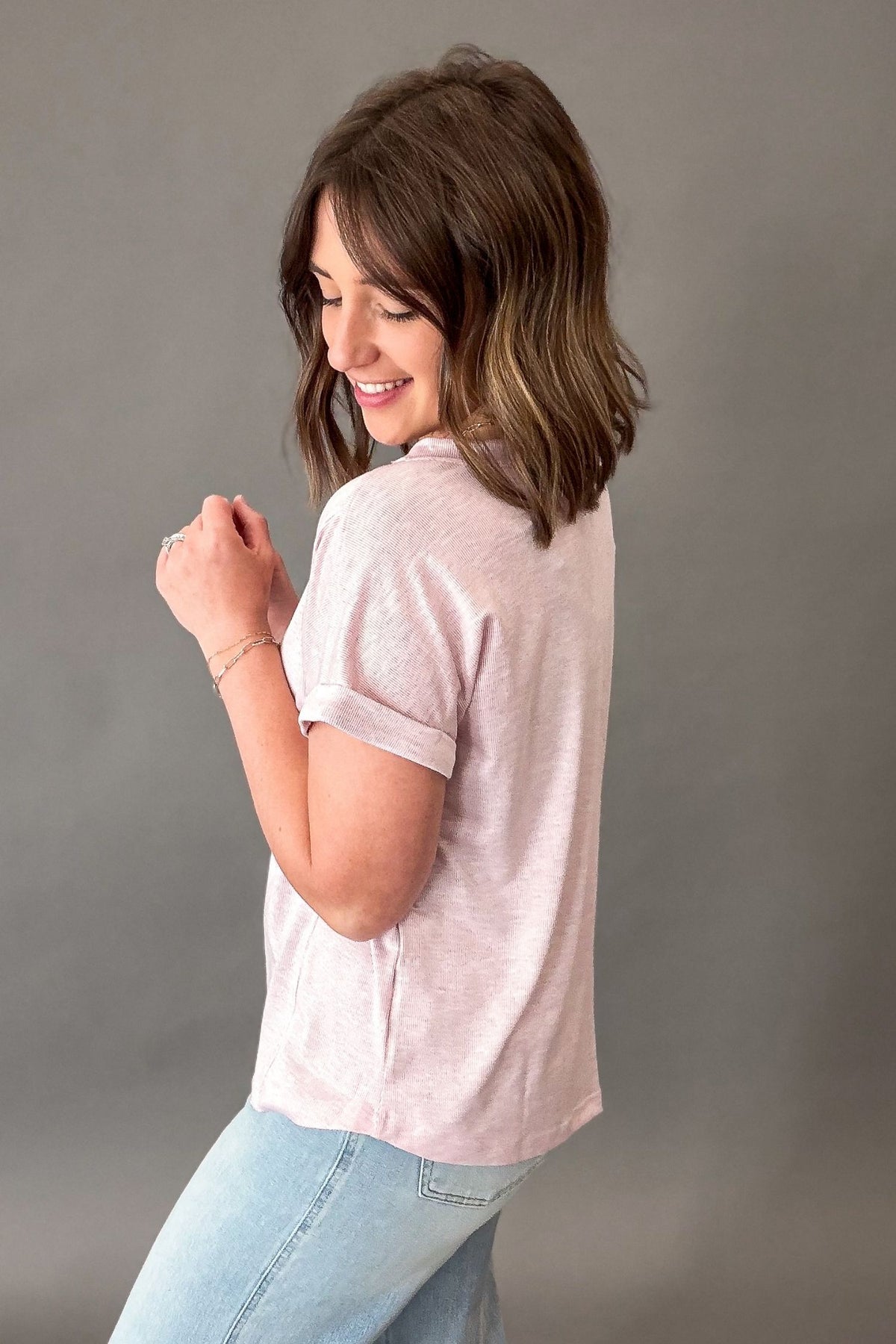 Woman wearing a light gray t-shirt and blue jeans against a plain background