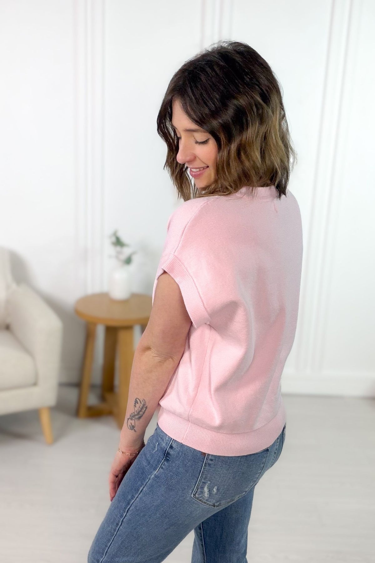 Pink v-neck button front sweater cardigan styled with blue denim showing the side/back details.