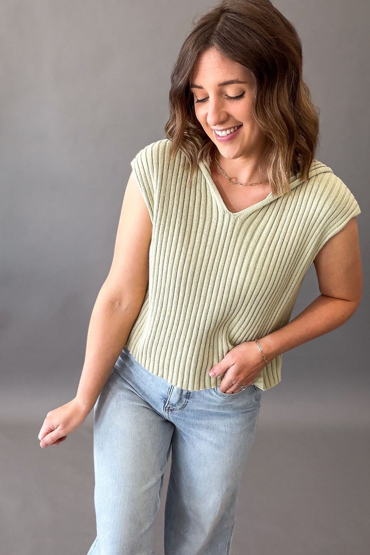 woman wearing a green v neck sweater hoodie tank