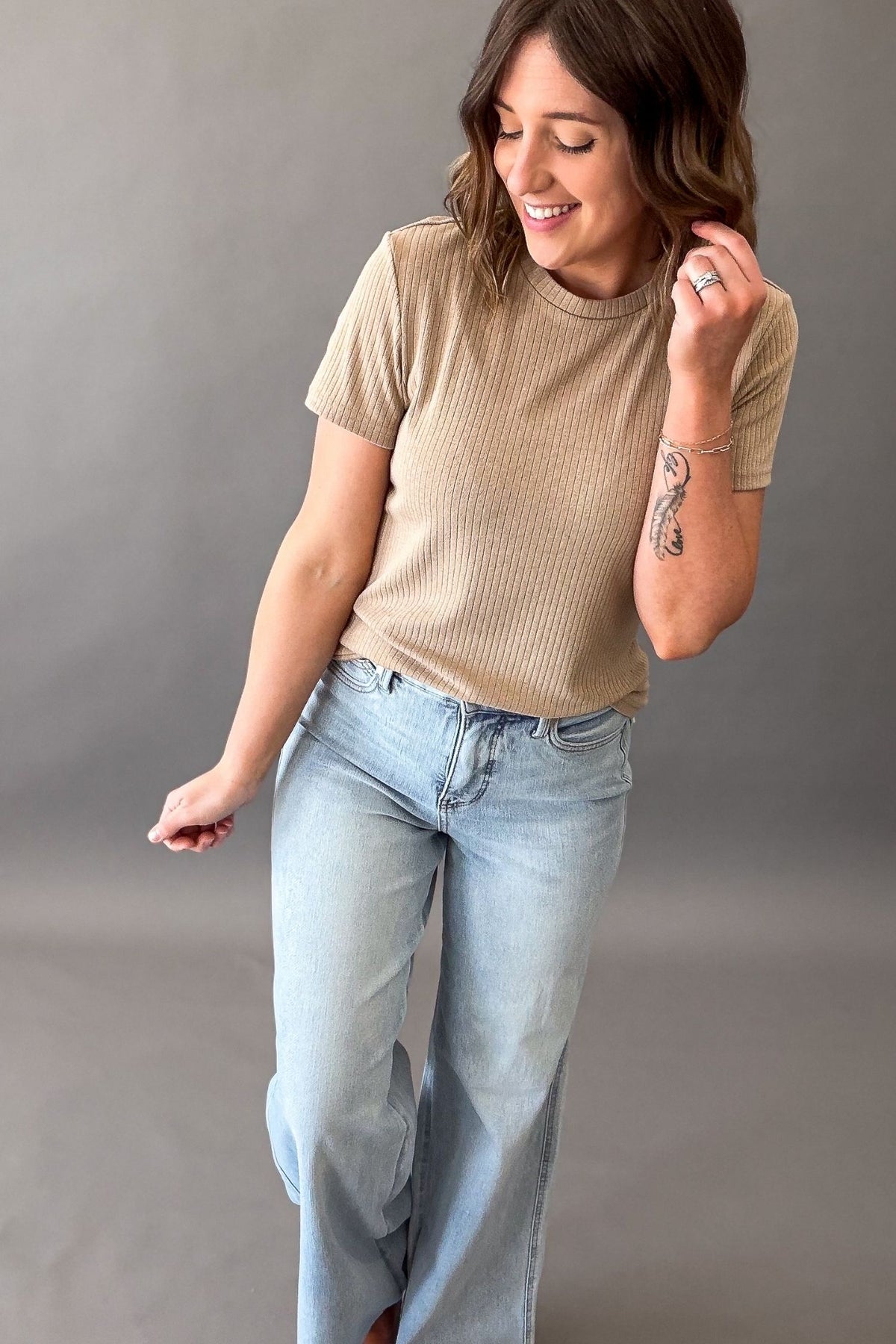 woman styling the pointelle knit top by tucking it in and pairing it with a light wash straight jean. 