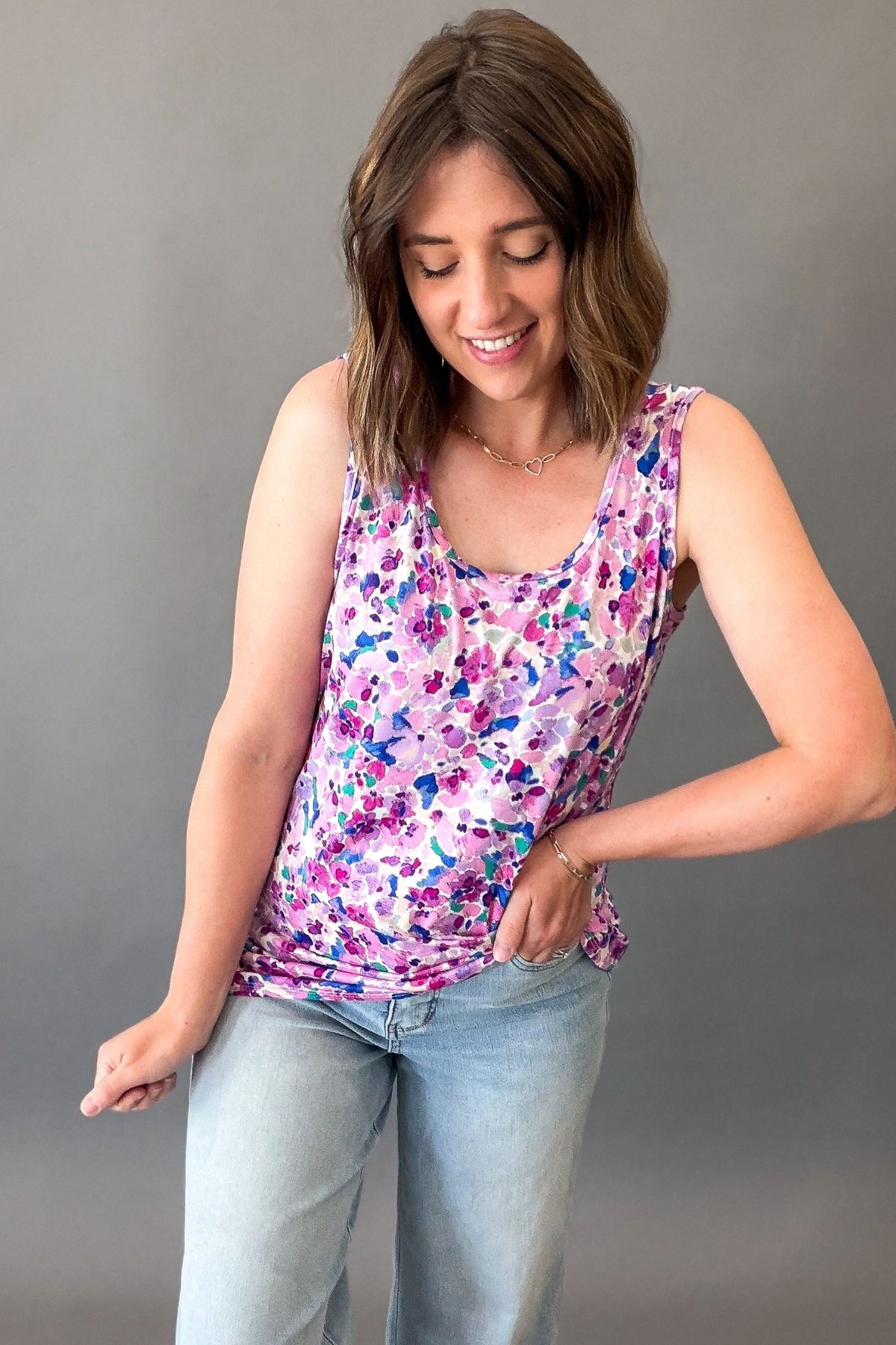 Woman wearing a purple floral sleeveless tank top featuring a colorful watercolor floral print and relaxed fit.