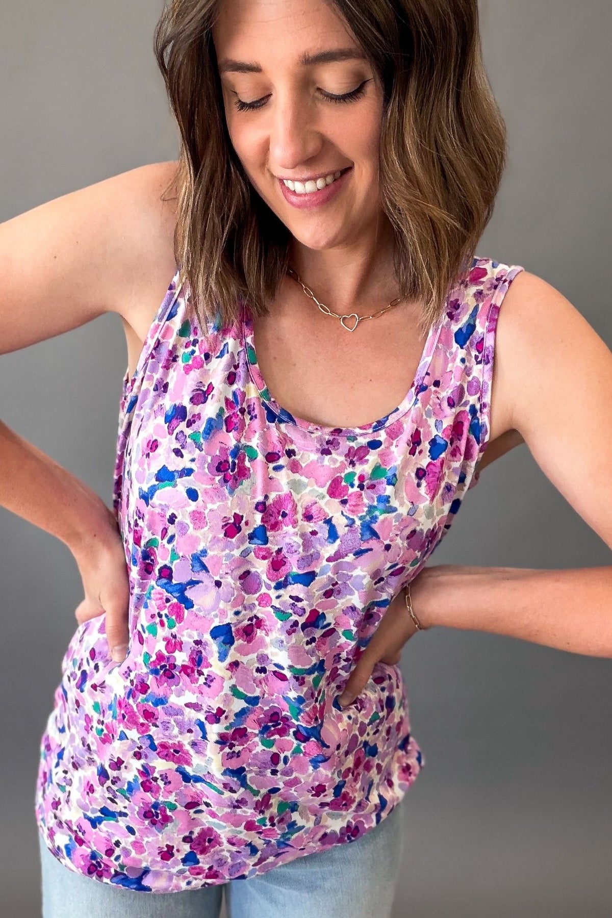 Woman wearing a purple floral sleeveless tank top featuring a colorful watercolor floral print and relaxed fit.