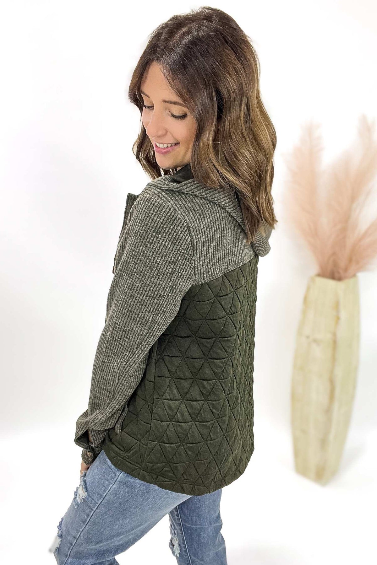 Woman wearing a green quilted button up with a plain background