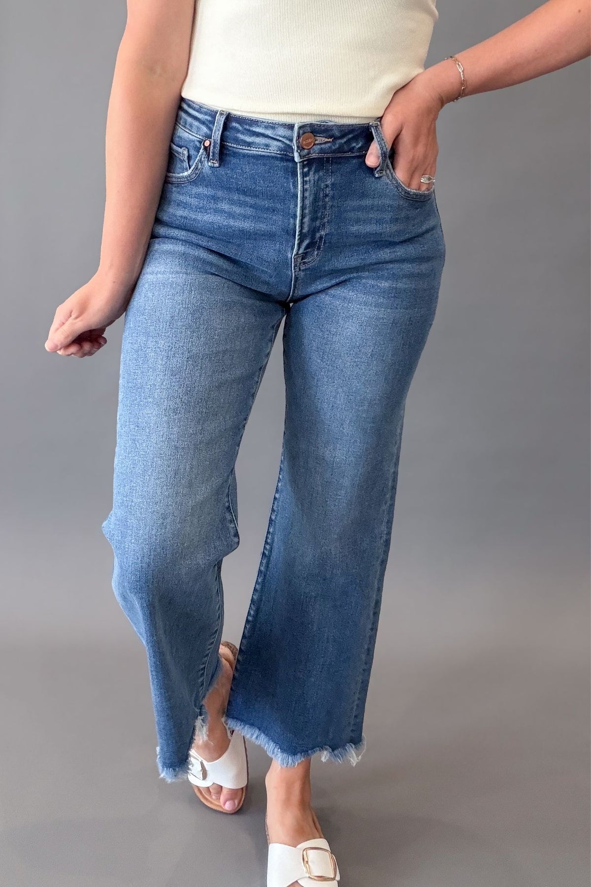 Woman wearing RISEN mid rise crop straight jeans with a medium wash, raw hem, and flattering straight-leg fit.