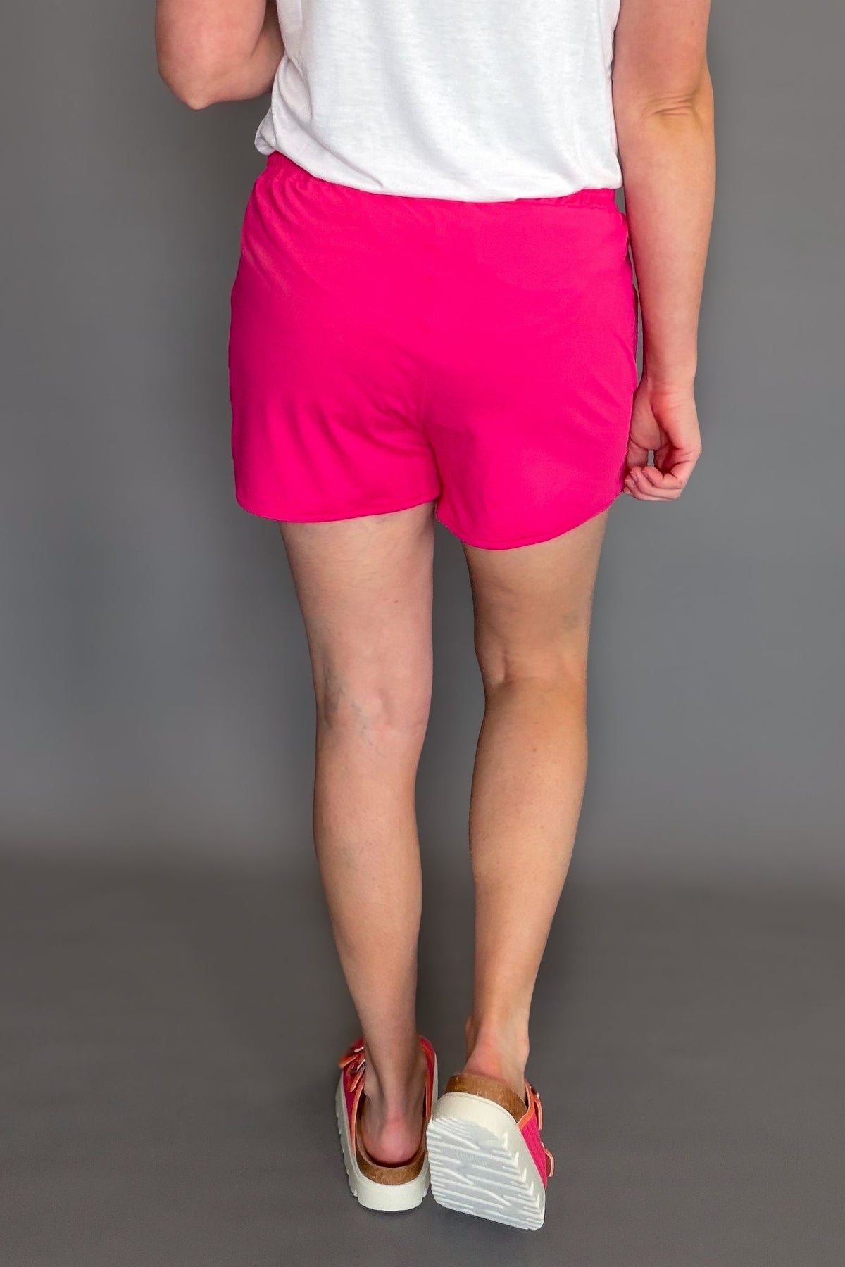 raspberry pink soft stretchy everyday shorts with drawstring waist and pockets styled with sneakers showing the back details