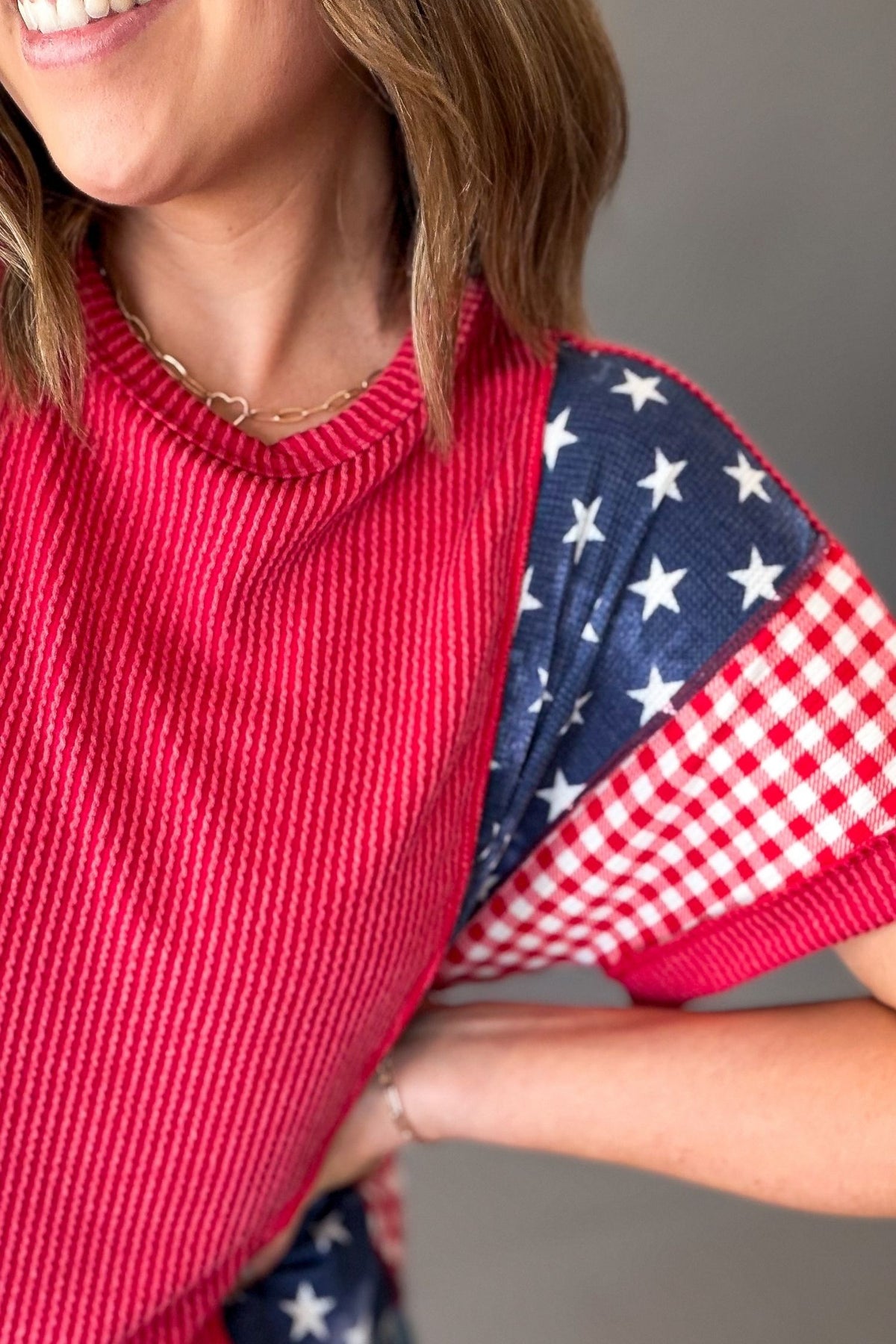 woman wearing a red white and blue short sleeve showing a closeup view of the ribbed texture with the waffle blue and white print with gingham print