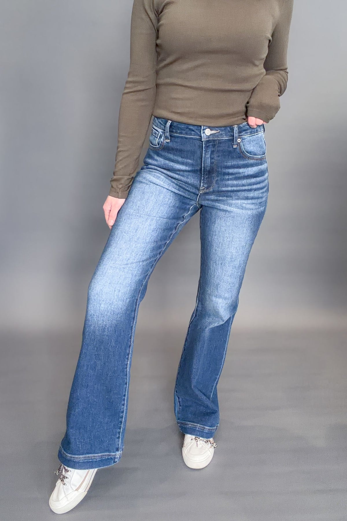 Person wearing blue jeans and a green top on a gray background