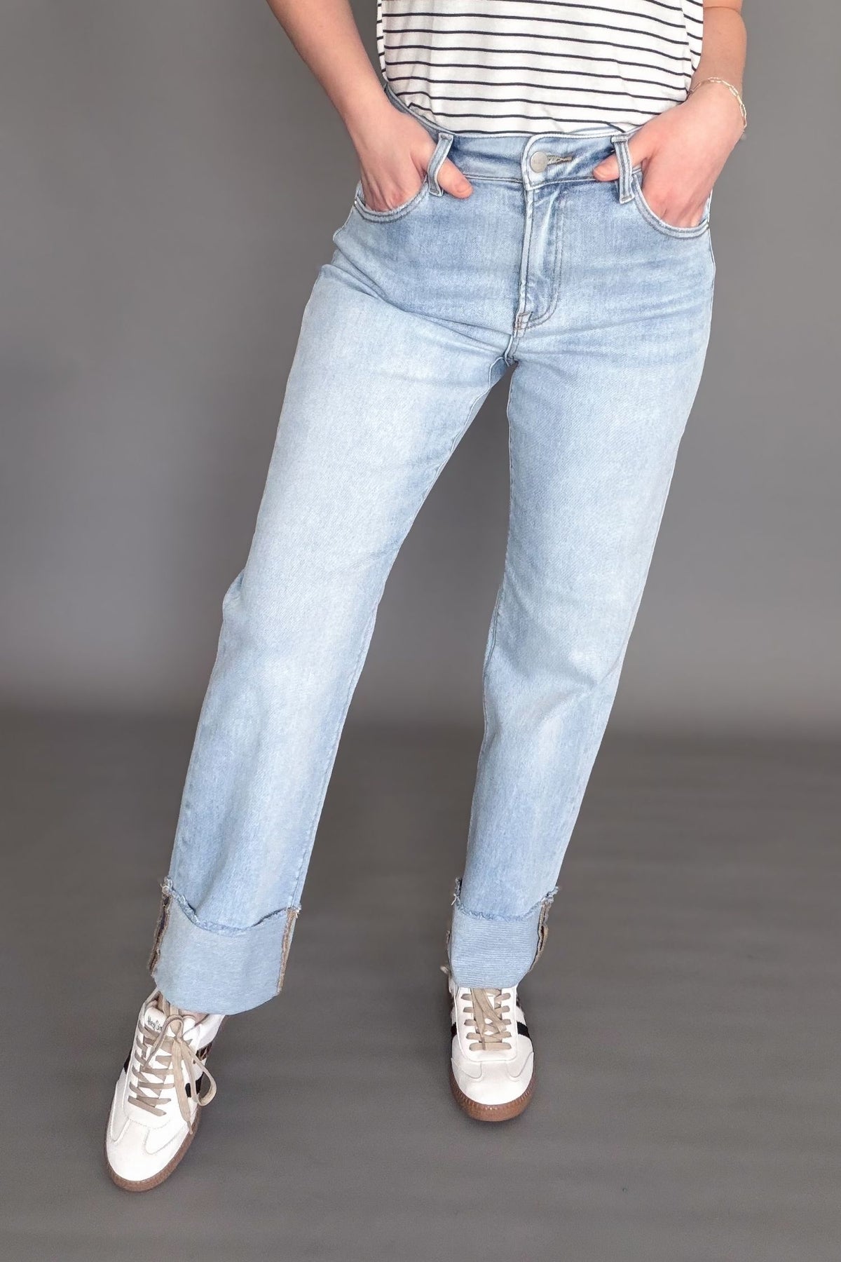 Woman wearing a light wash risen high rise straight cuffed denim on a dark grey background showing the front view