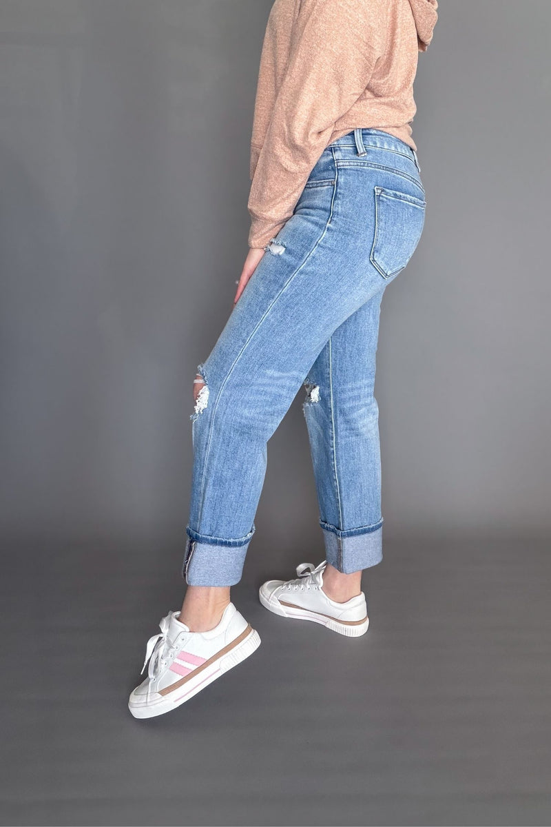 Person wearing blue jeans and white sneakers on a gray background