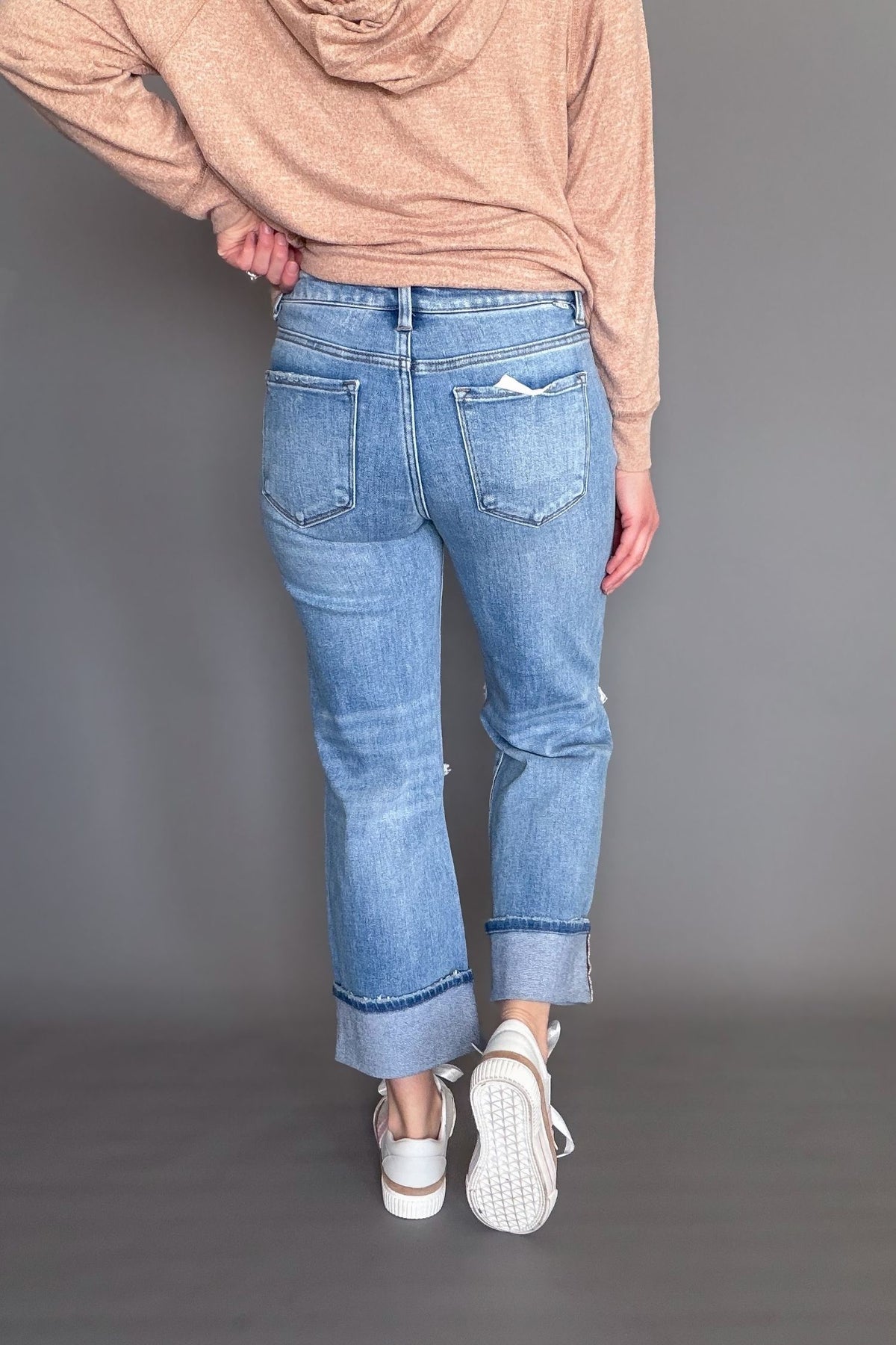 Person wearing blue jeans and a orange hoodie on a gray background