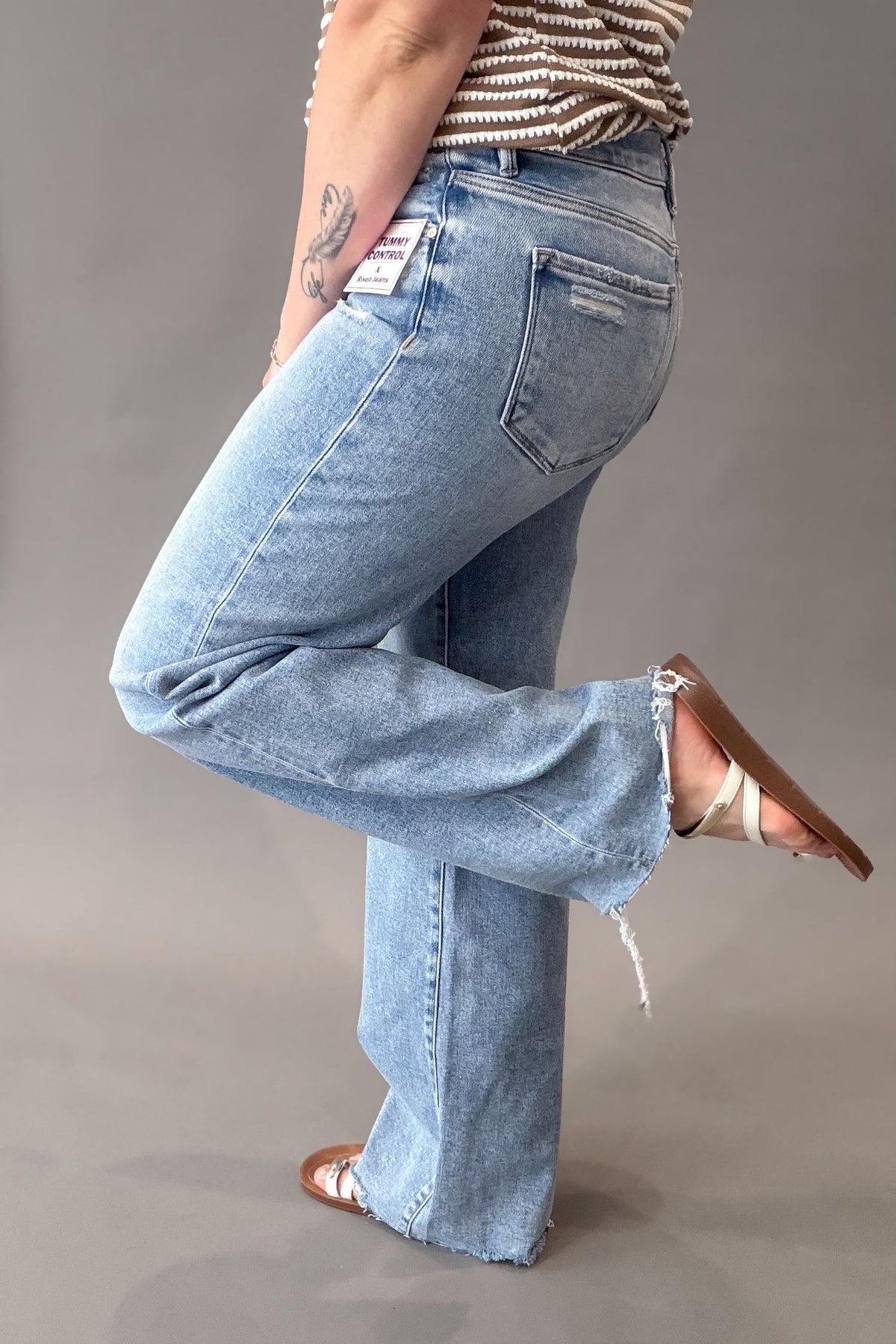 Woman wearing a comfortable pair of risen light wash jeans with light distressing showing the side and back details
