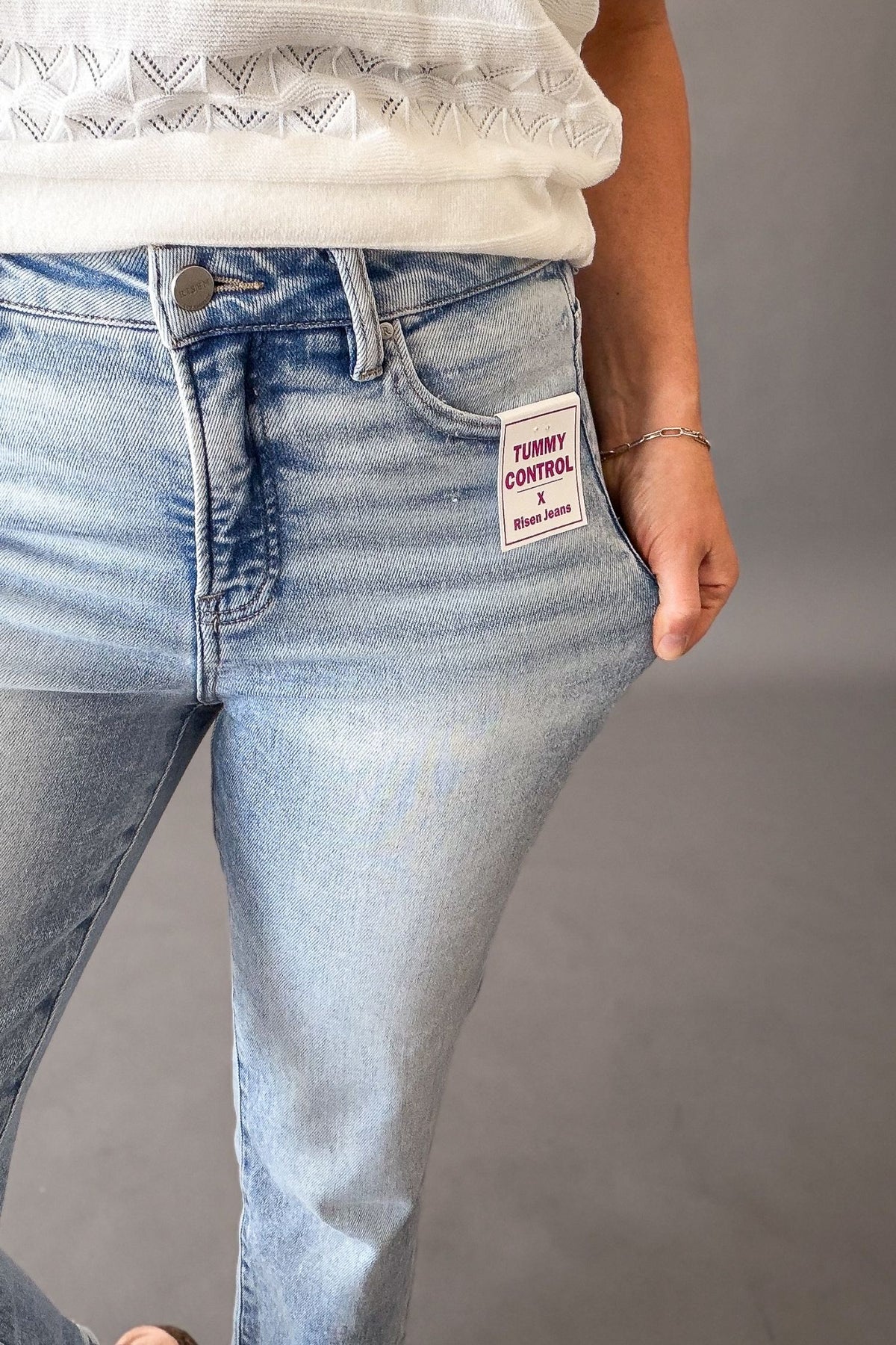 Woman wearing Risen high rise tummy control straight leg jeans with cuffed hem, light wash cropped denim for women showing the light stretch