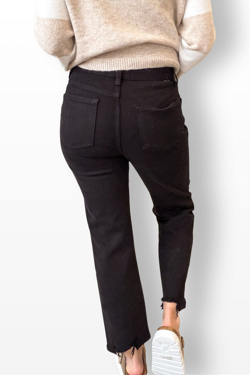 Black pants worn with a beige sweater on a white background