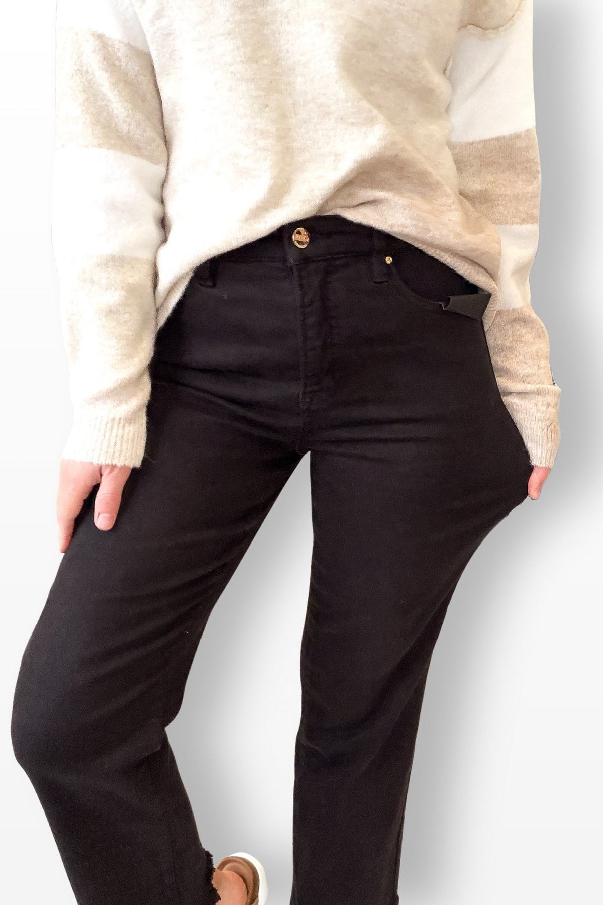 Person wearing black pants and a beige sweater on a white background