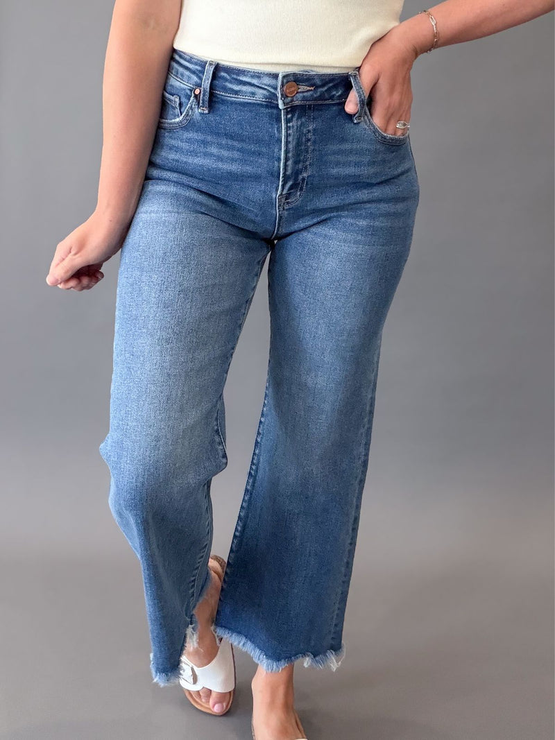 Person wearing blue RISEN jeans on a gray background