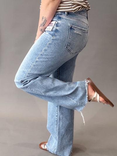 Person wearing light blue risen jeans on a plain background