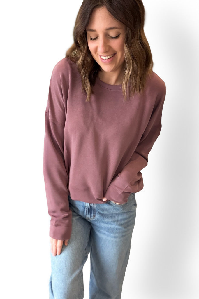 Woman wearing a rose sweatshirt and light blue jeans on a white background