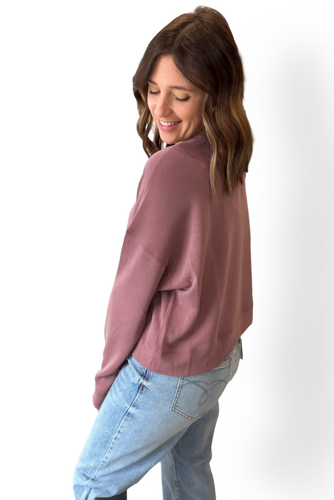 Woman wearing a rose sweater and light blue jeans on a white background