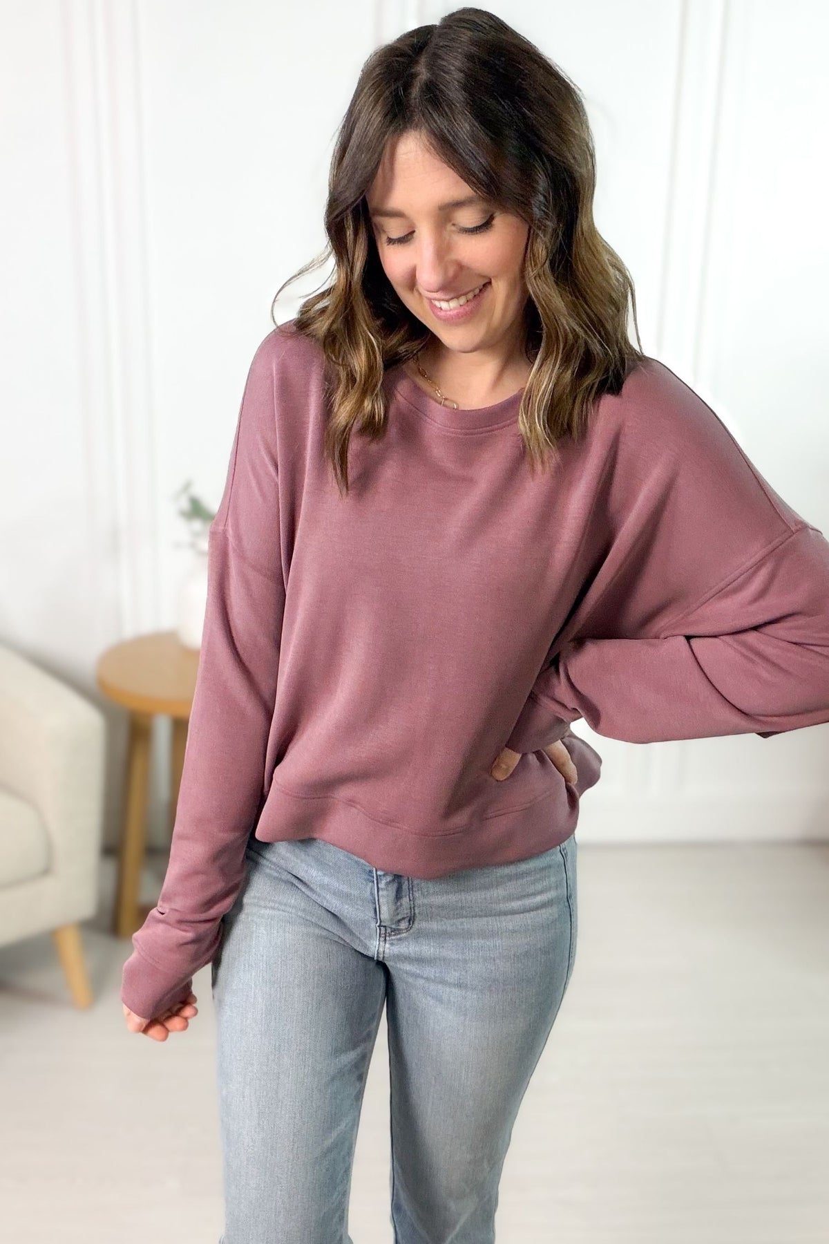 Woman wearing a rose super soft sweatshirt and light blue jeans indoors.