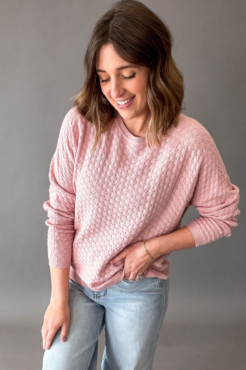 Woman wearing a rose pink pointelle knit sweater with lightweight soft fabric and stretch, casual everyday sweater for women